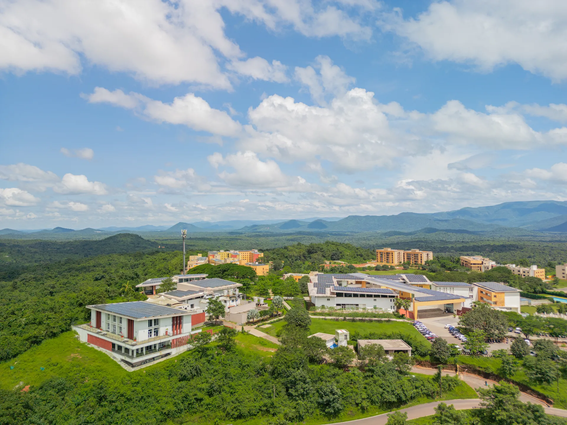 Aerial view of the GIM campus amid forested hills